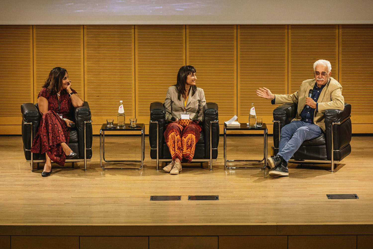 Sara Hejazi, Riccardo Cristiano e Katia Malatesta sul palco durante una conferenza. Quest'ultimo sta parlando al microfono.