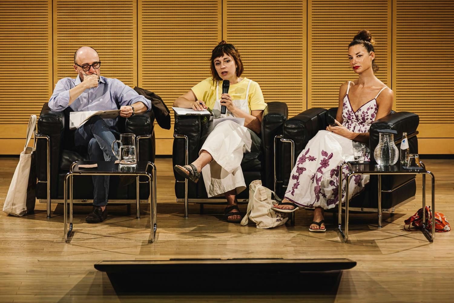Tre persone sul palco, durante una conferenza. Un uomo e una donna. Sulla destra Gaia Vince.