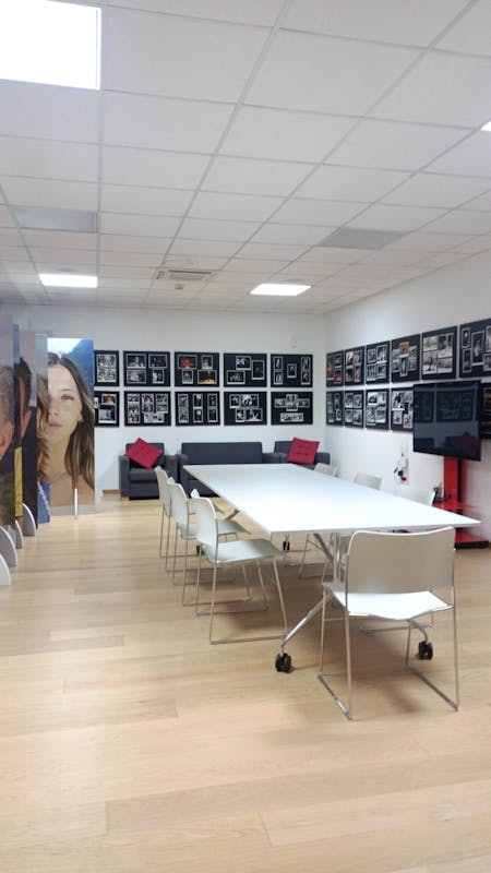 Sala riunioni al primo piano dello Studio con un grande tavolo bianco e sedie, uno schermo e tante foto sulle pareti