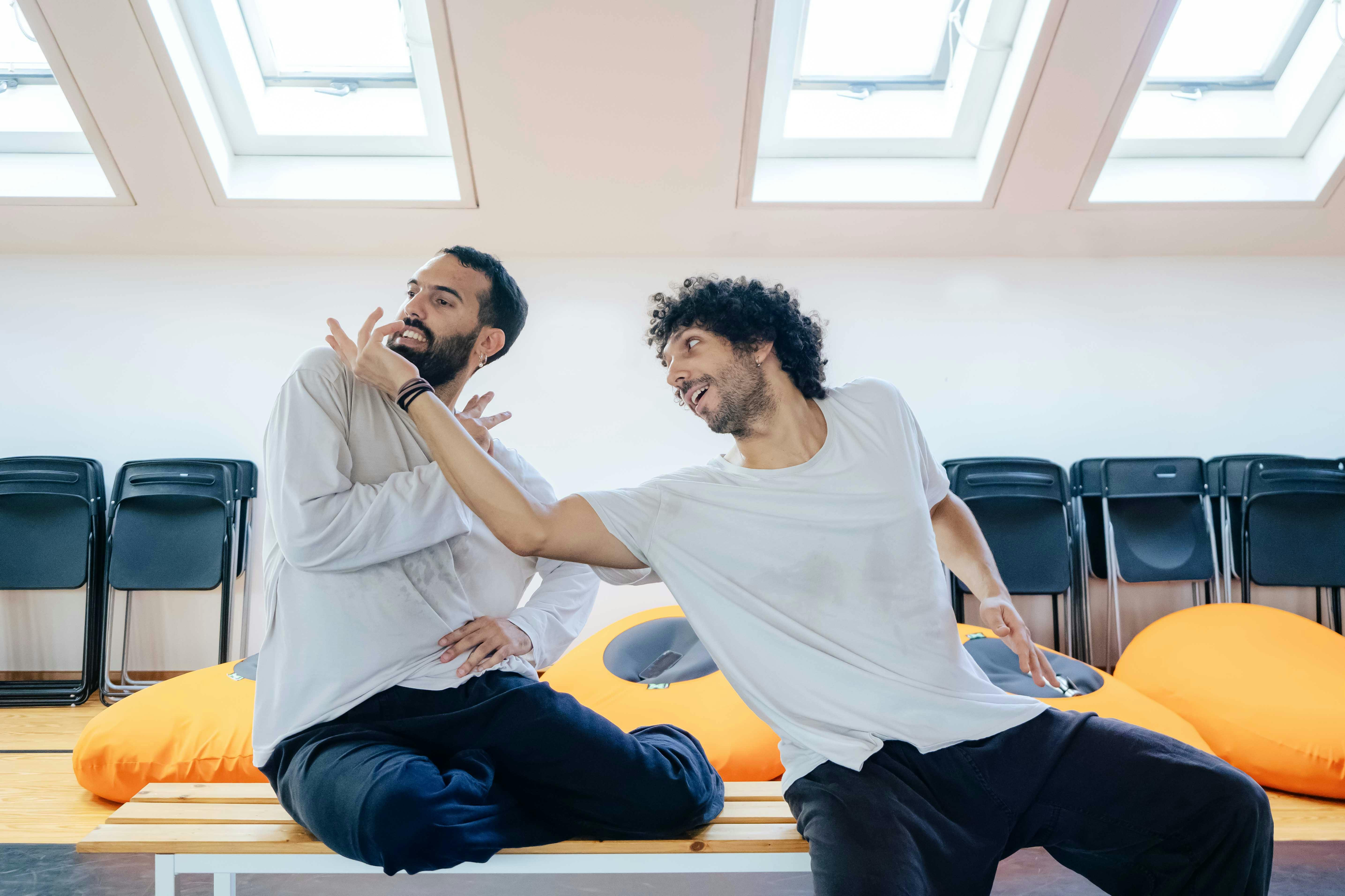 I due danzatori seduti su una panchina indossano maglie bianche