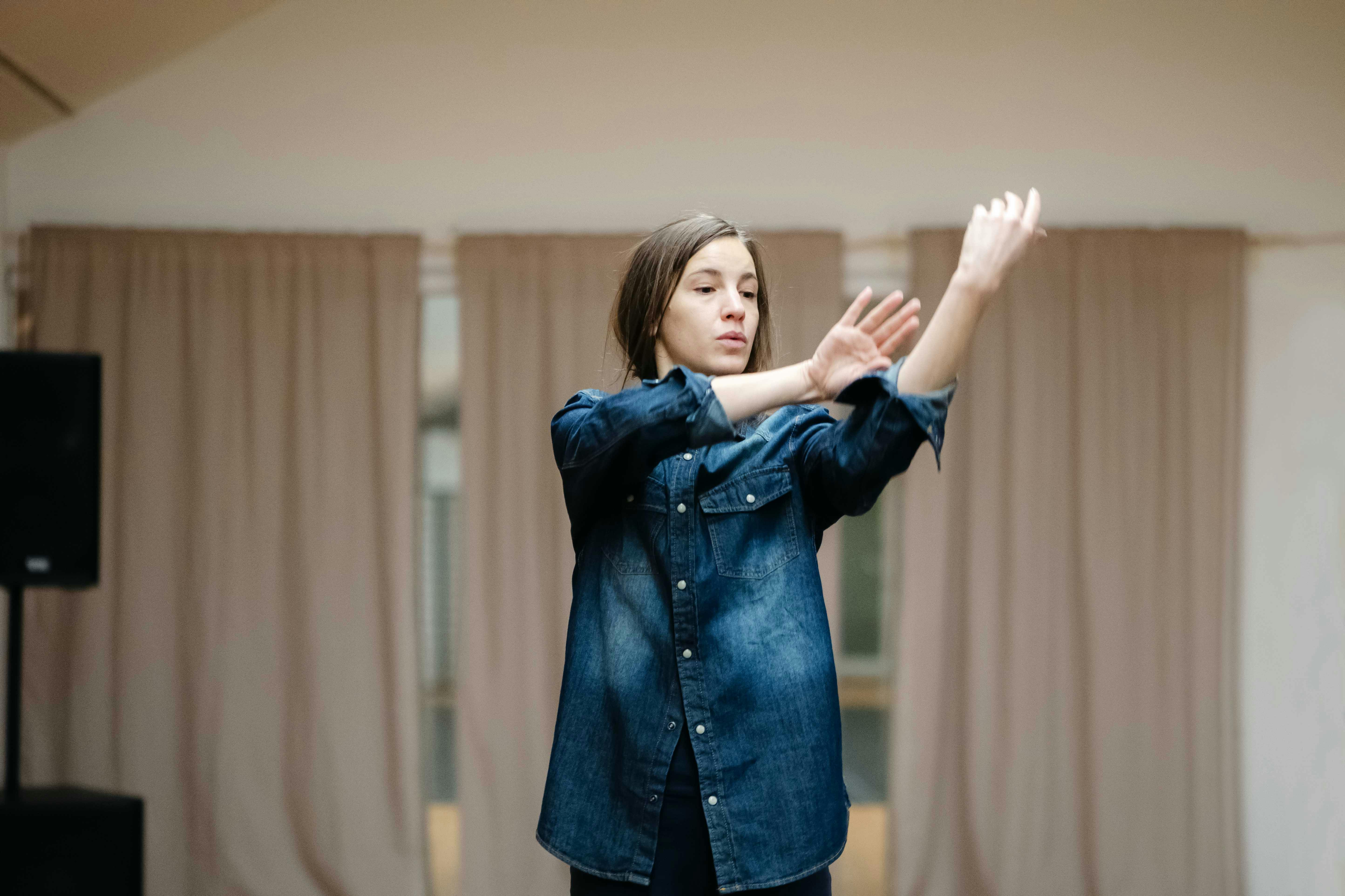 Half-length photograph of Stefania Tansini wearing blue denim shirt and blue trousers, arms forward and stretched to the right