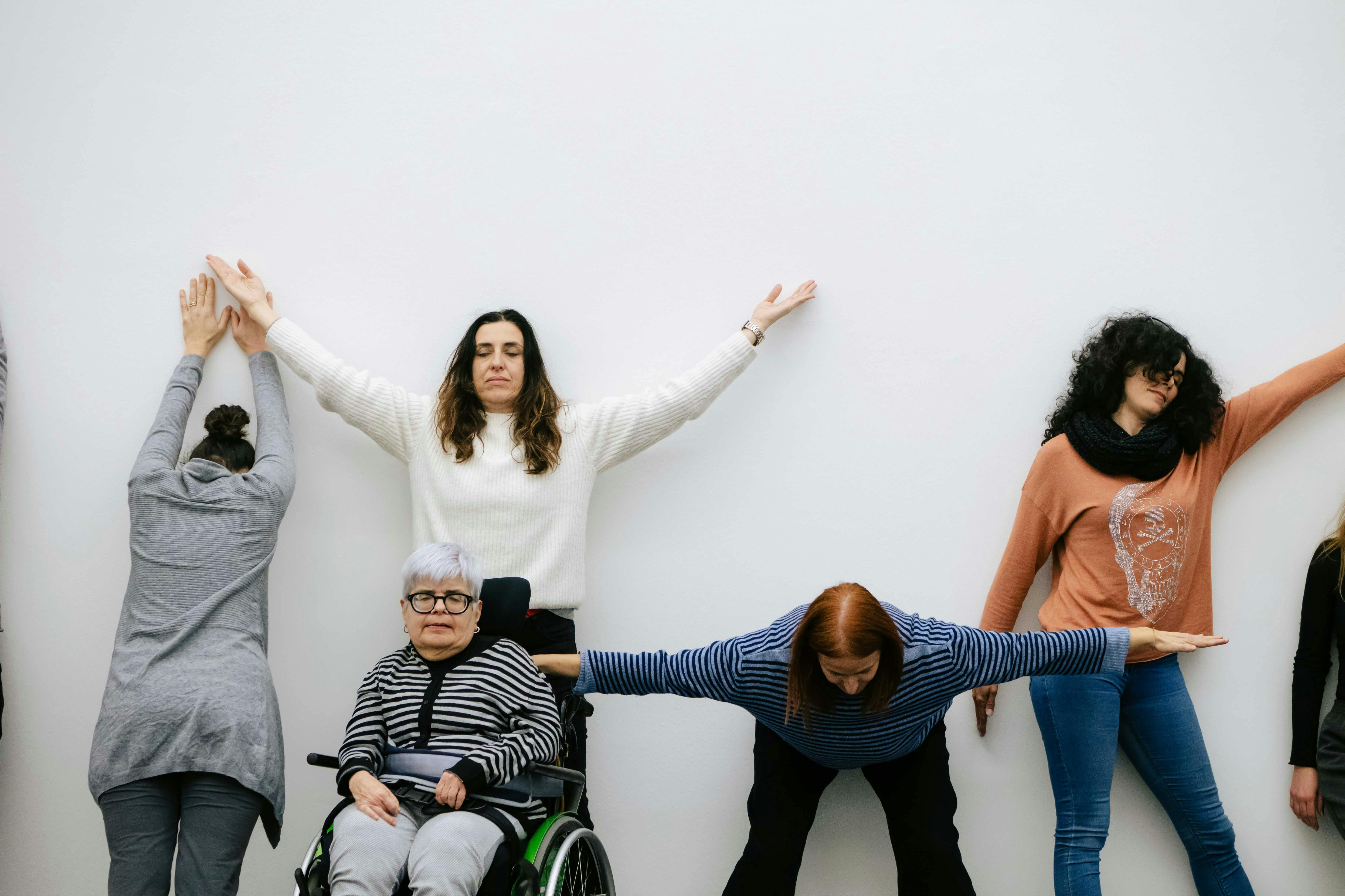Un gruppo di persone tengono diverse posizioni su un muro bianco