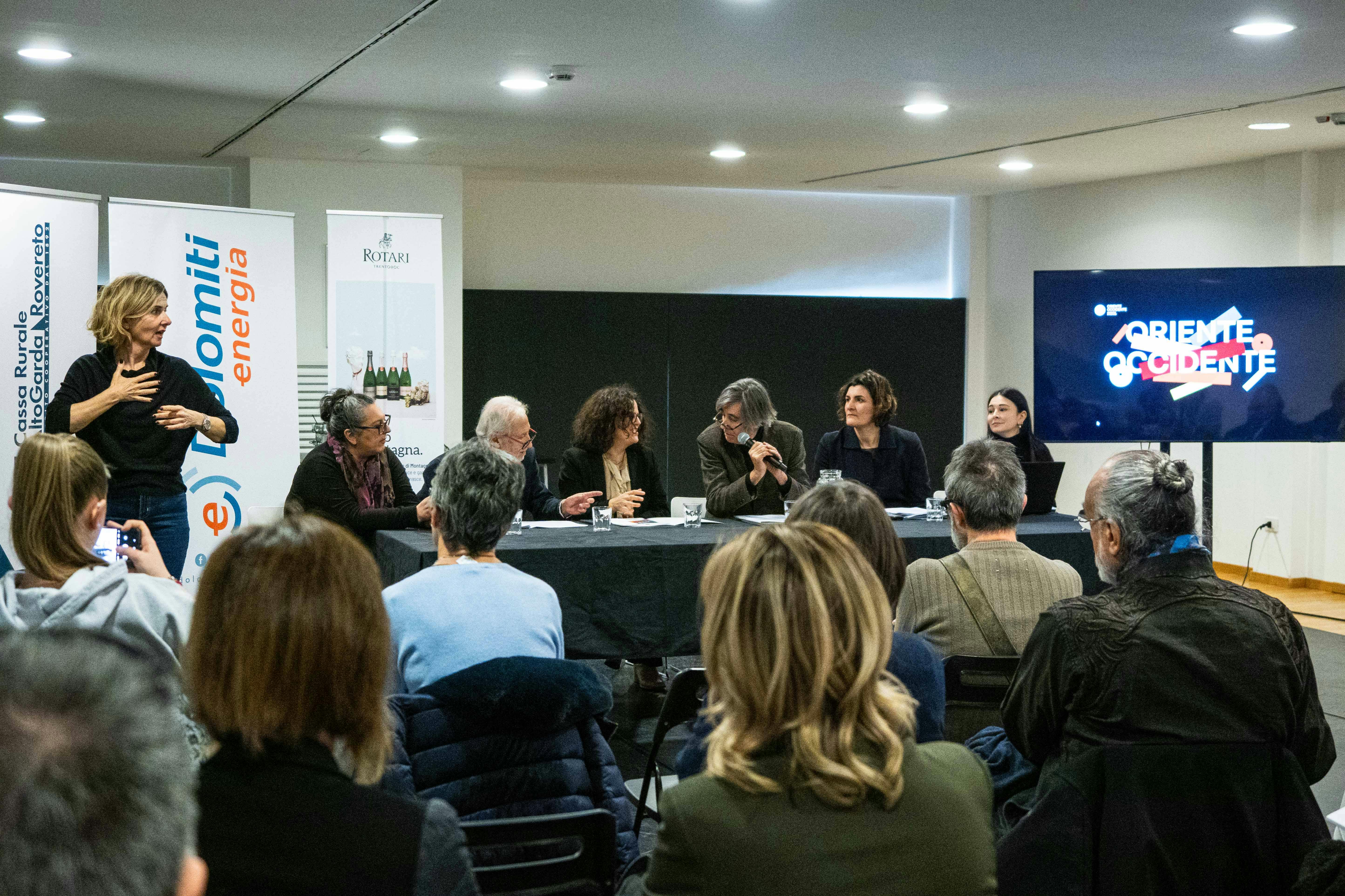 Fotografia della conferenza stampa di lancio delle attività 2025 con un tavolo di relatori, una traduttrice LIS e pubblico di schiena