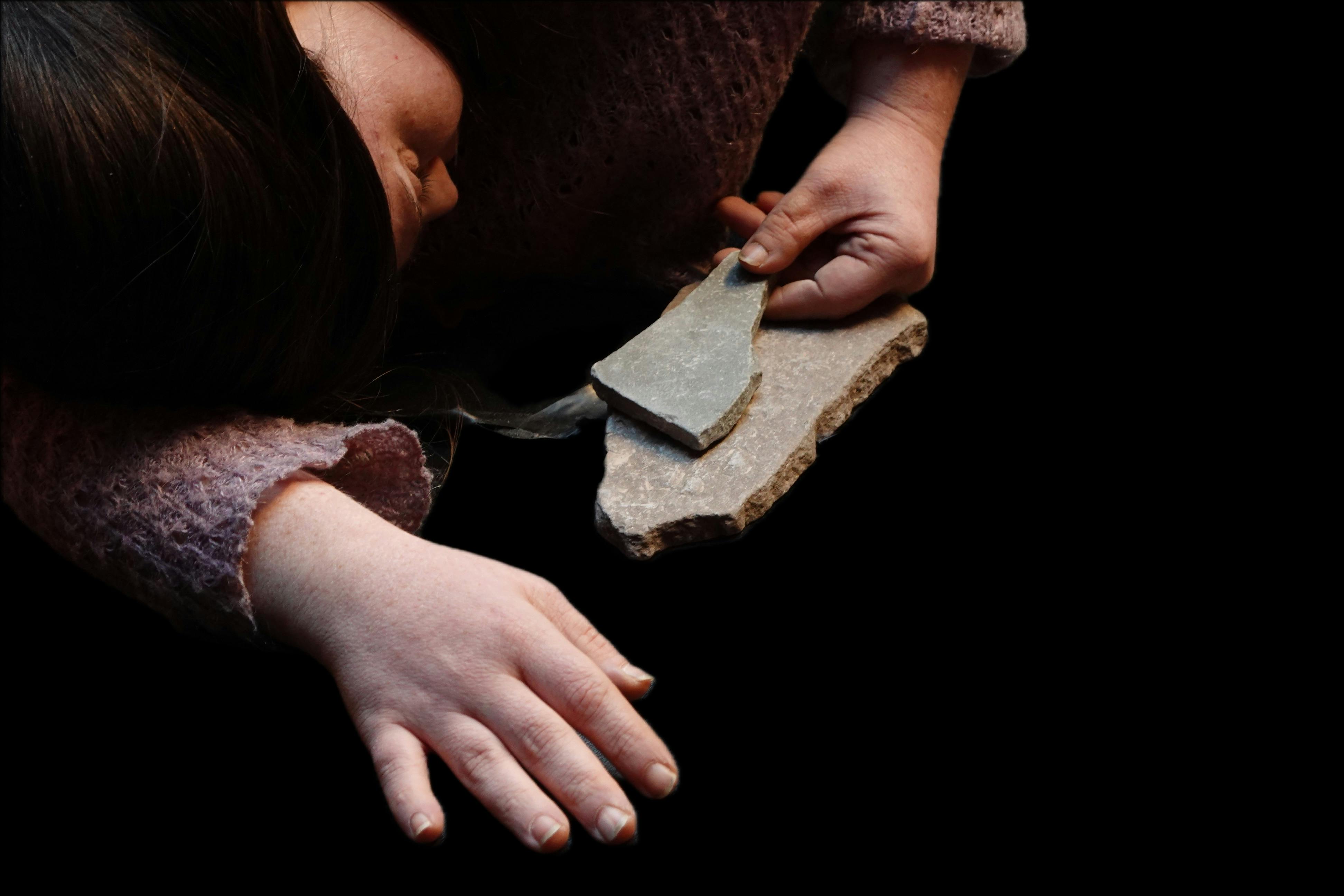 Fotografia della danzatrice Laura Lucioli sdraiata che tiene in mano un frammento di pietra