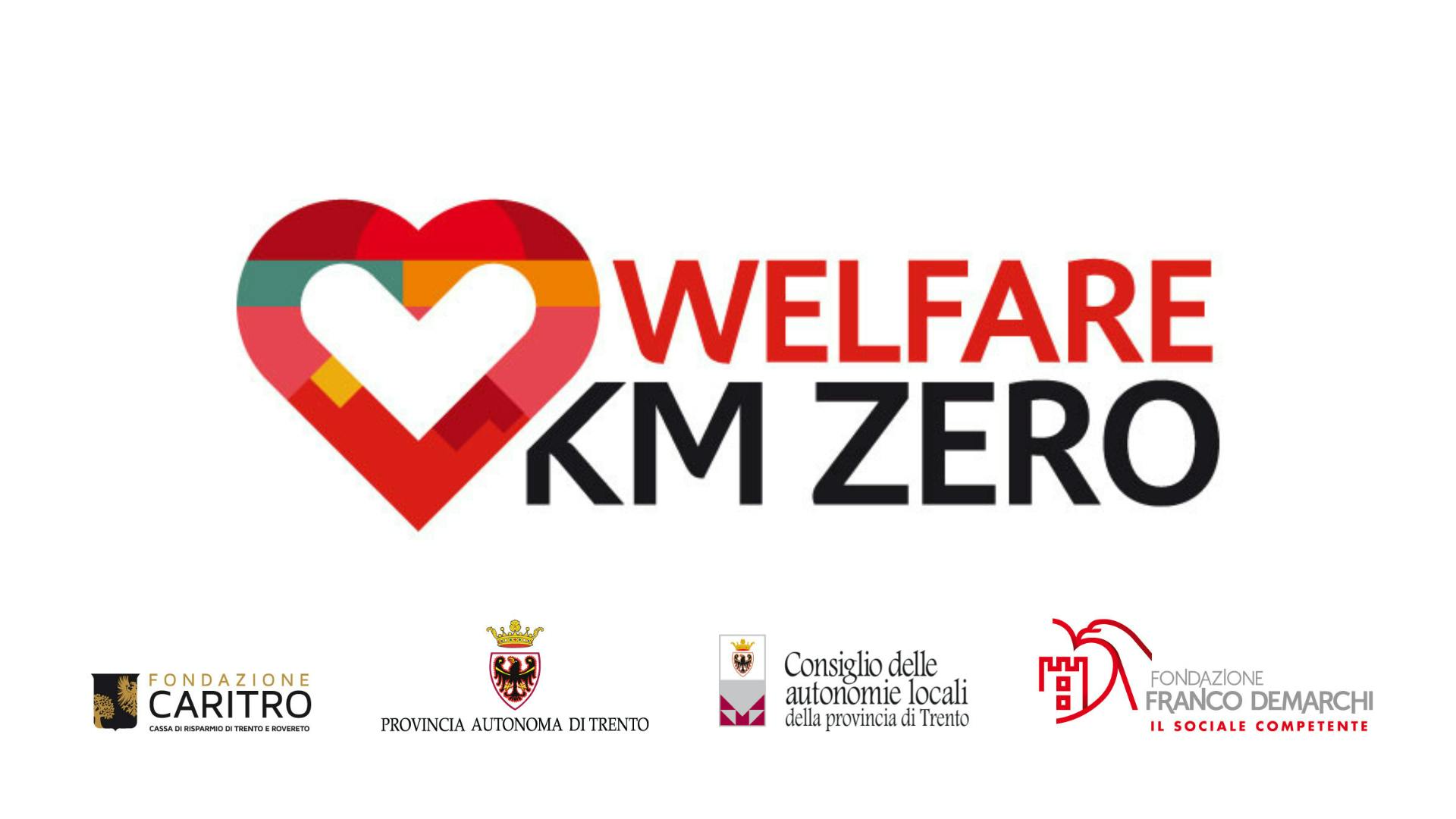 Sfondo bianco con quattro loghi a colori sulla banda inferiore e un logo più grande centrale con un cuore sulla sinistra e la scritta "Welfare km zero"