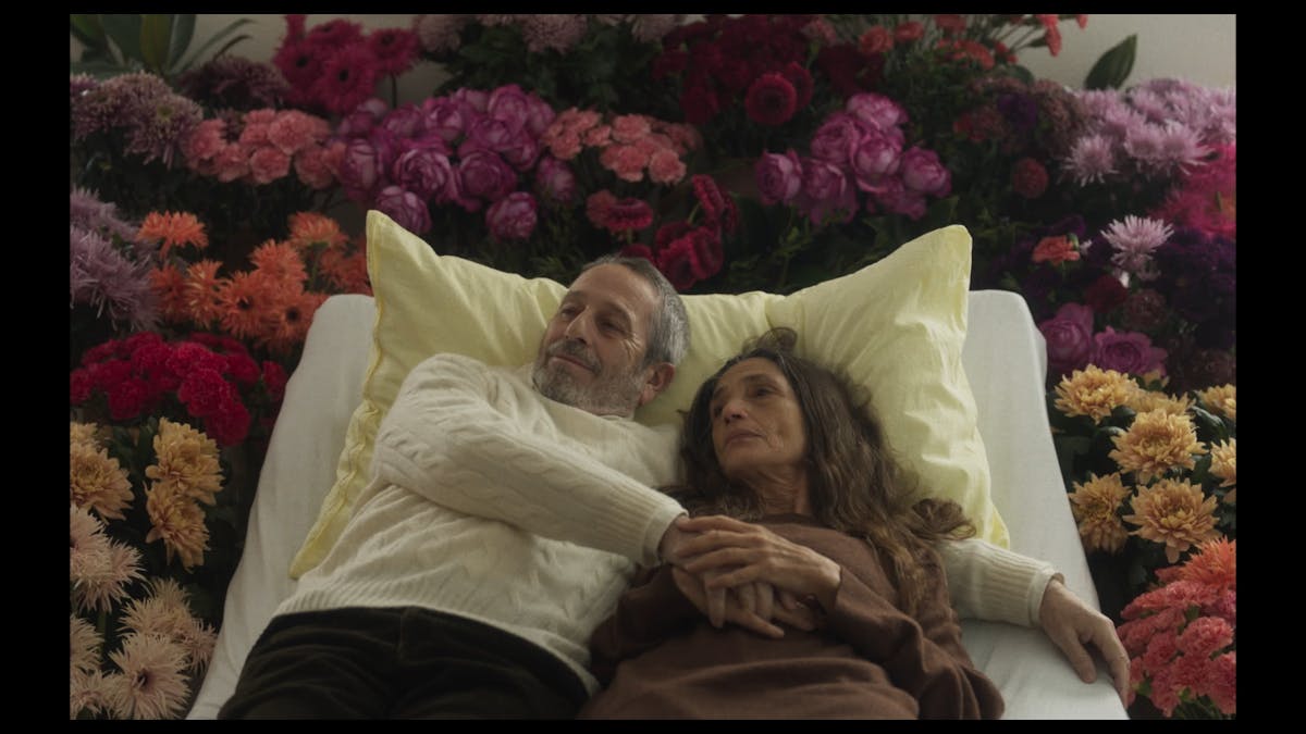 Un uomo e una donna sono abbracciati su un letto circondato da fiori colorati
