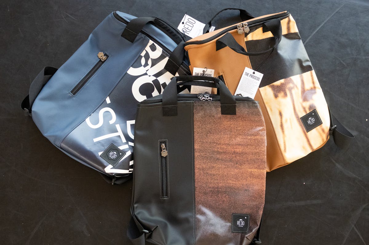 Tre zaini della nuova collezione, uno nero e marrone, uno blu con delle scritte e uno beige e marrone chiaro