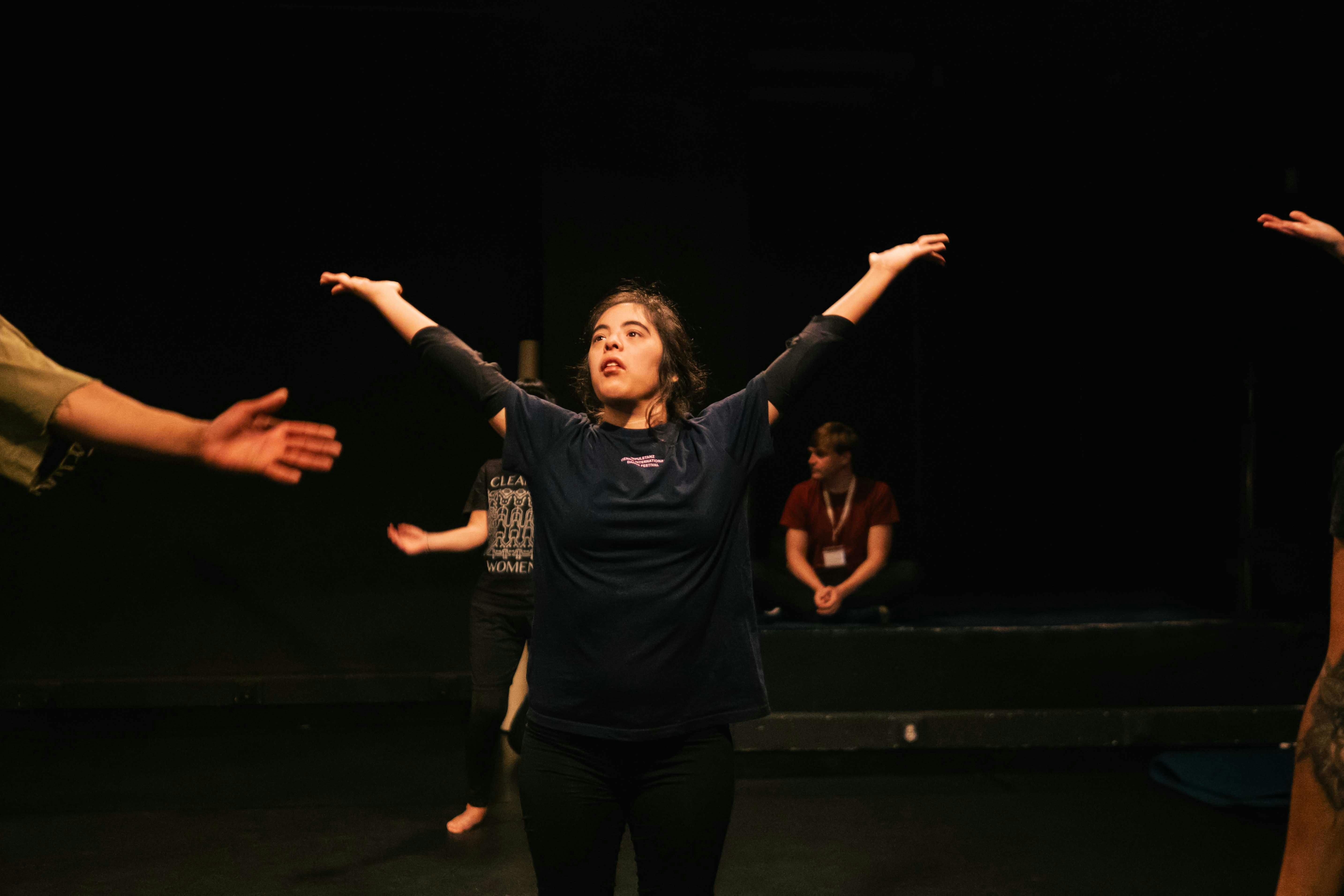 Una danzatrice con disabilità alza le braccia al cielo