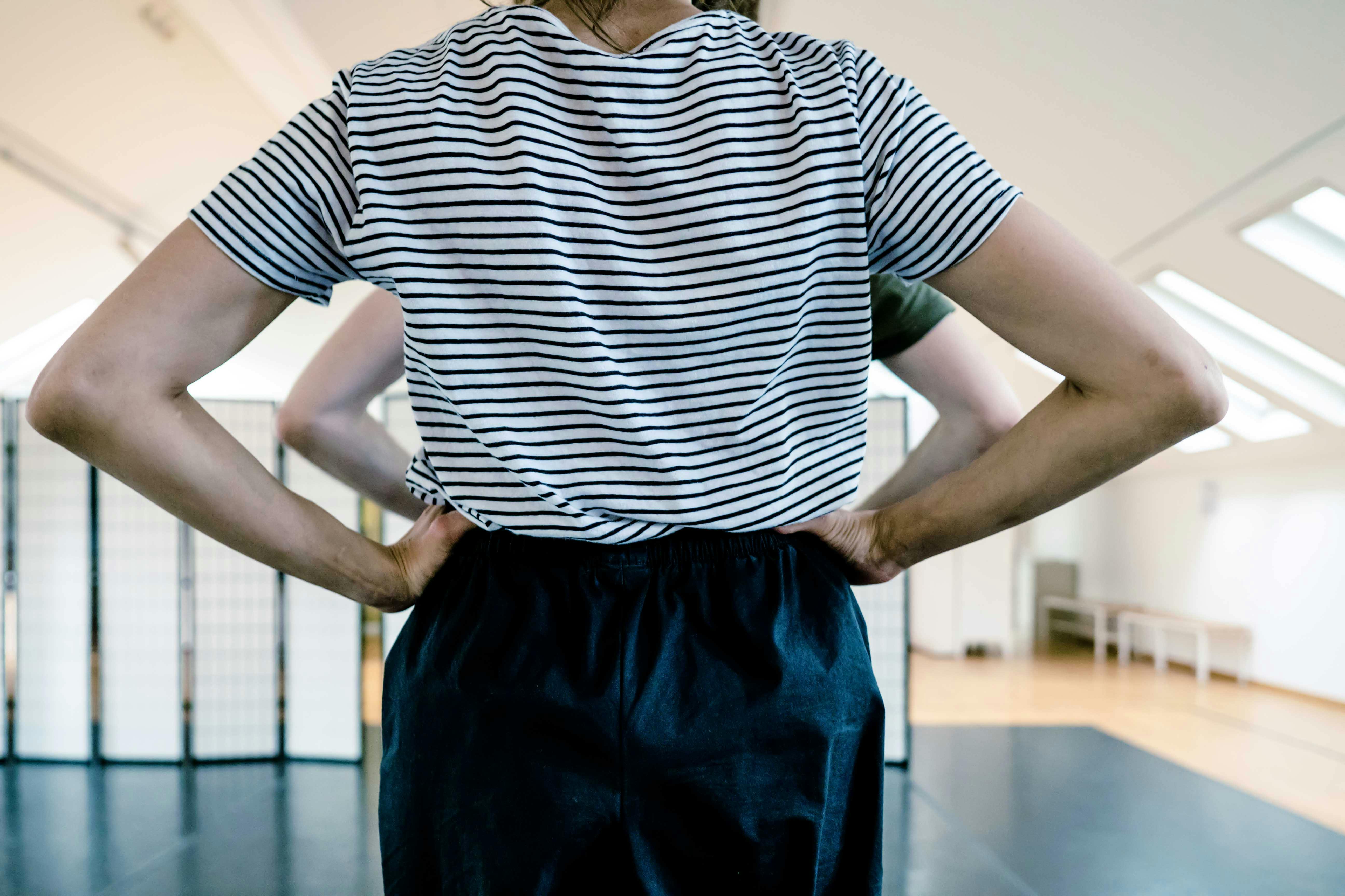 Due persone una dietro l'altra di schiena con le mani sui fianchi