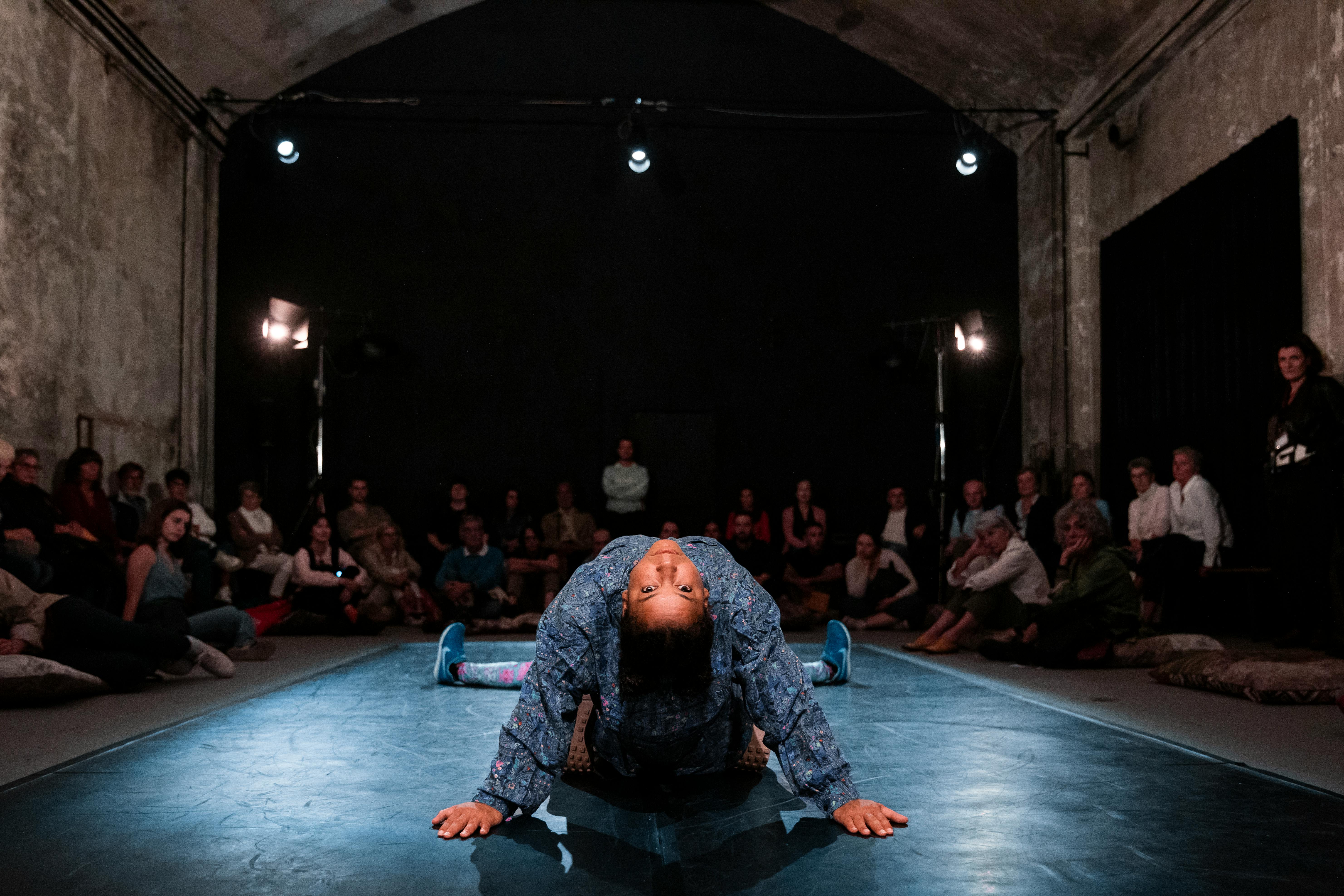 Momento performativo in cui una danzatrice fa un ampio arco con la schiena guardando in camera