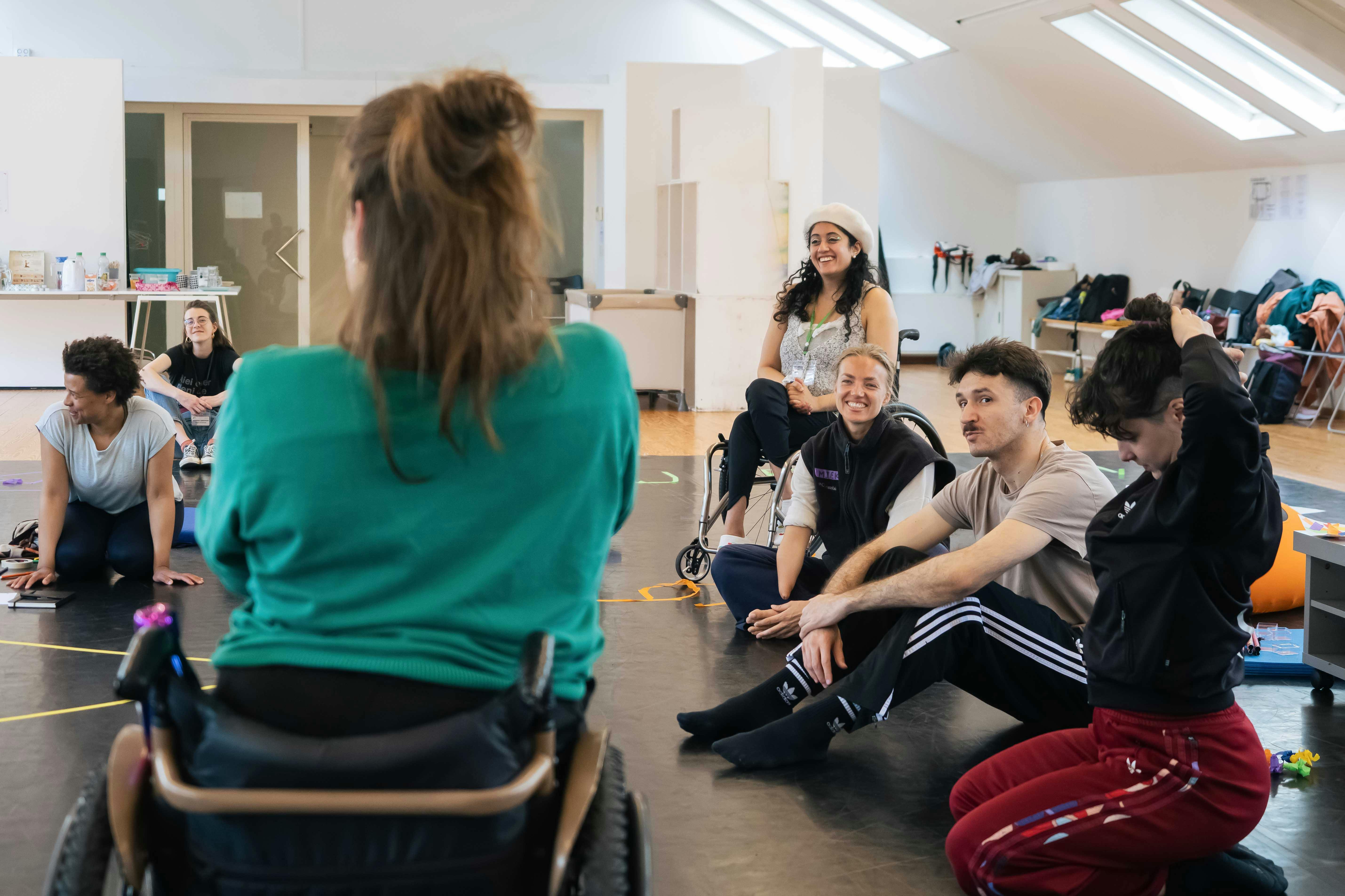 Un gruppo di artisti e artiste con disabilità lavorano e si confrontano in sala danza
