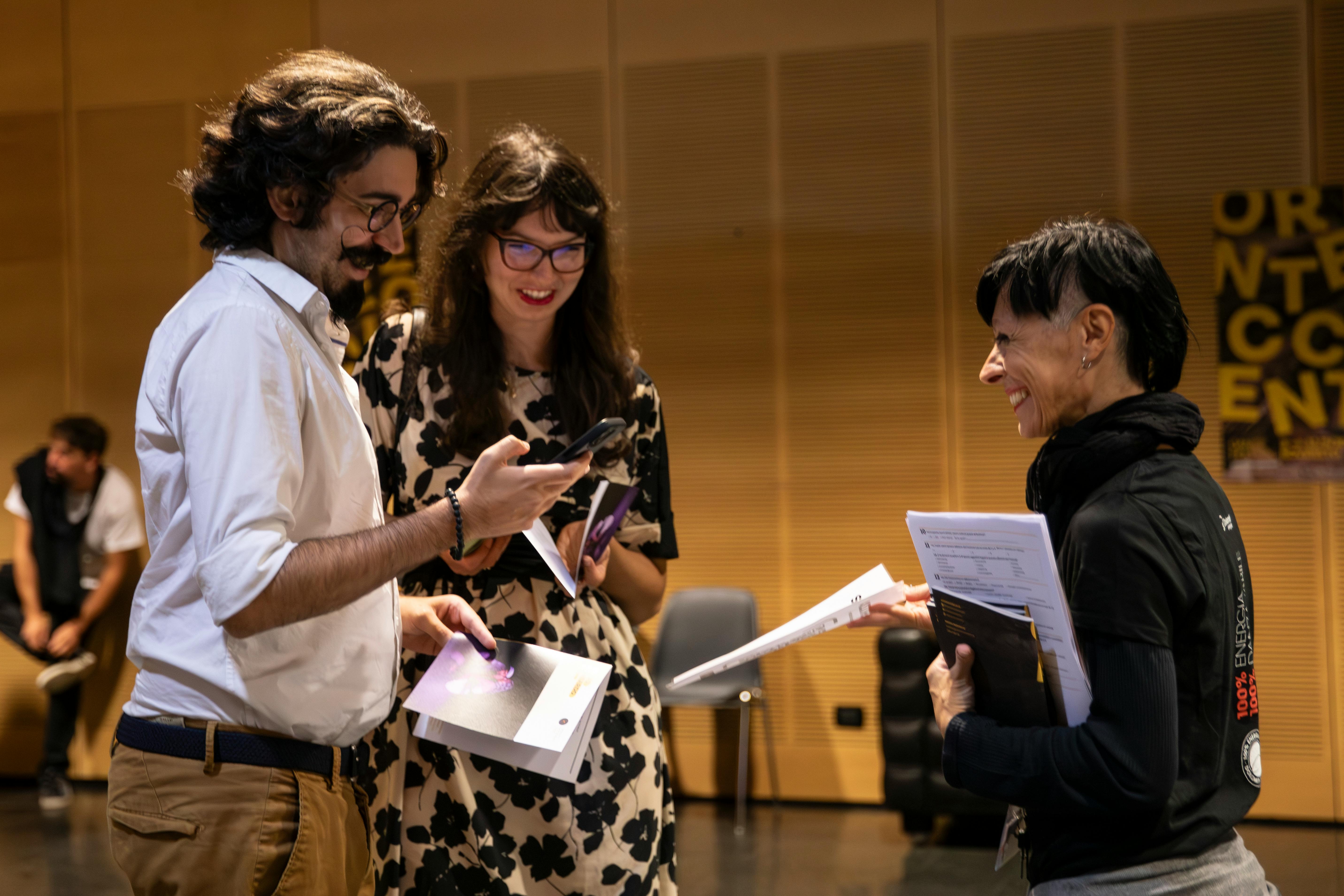 Una volontaria del festival propone di compilare il questionario a due giovani