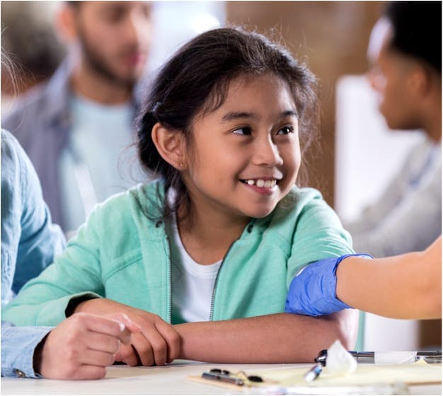 Young girl smiling as she is examined by a doctor