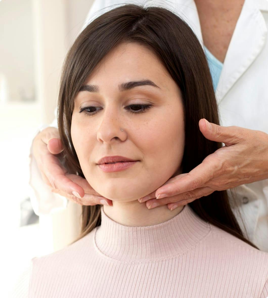 a doctor giving a woman a pink top a throat exam