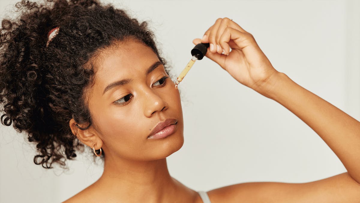 an image of a woman applying a facial serum on her cheeks