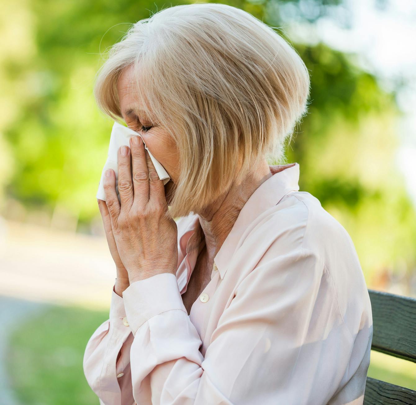 an image of an older woman blowing their nose into a tissue