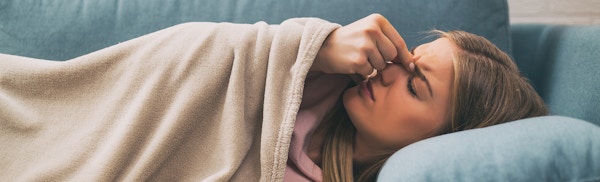 Women Laying On Her Couch Touching Her Nose