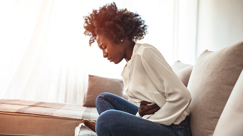 Woman with her hand on her stomach leaning forward.