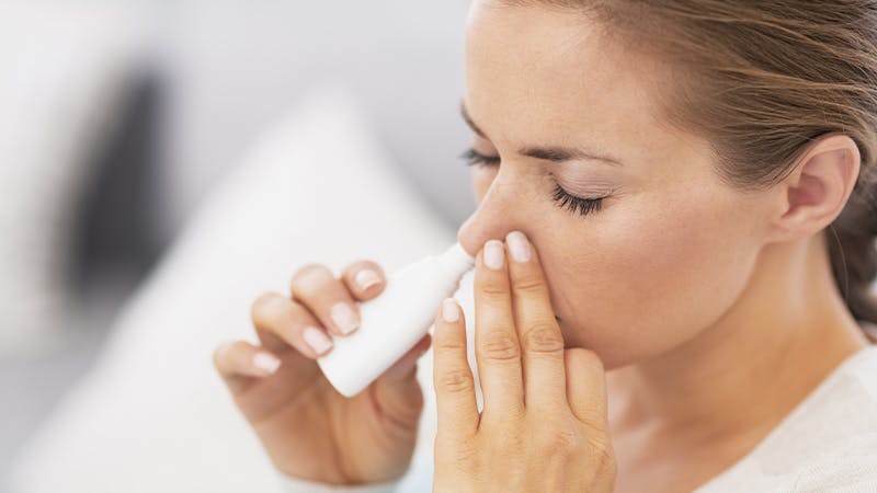 Woman using nasal spray.