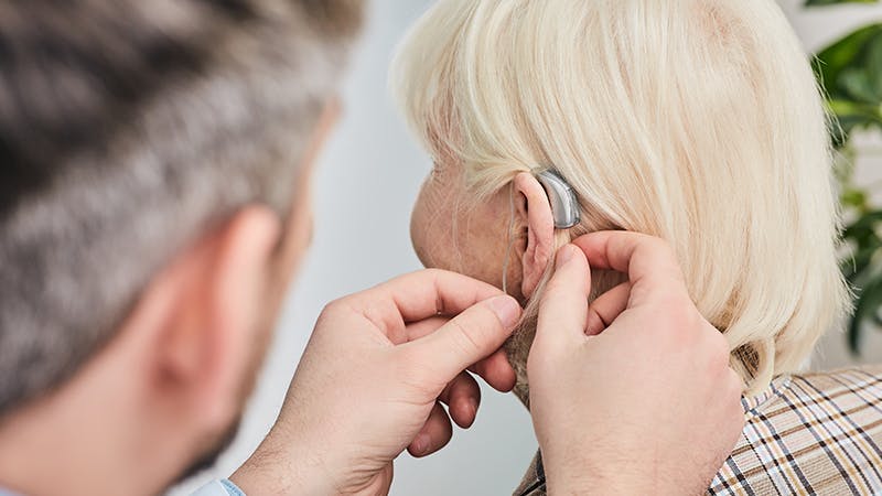 Physician adjusting a patient's hearing aid
