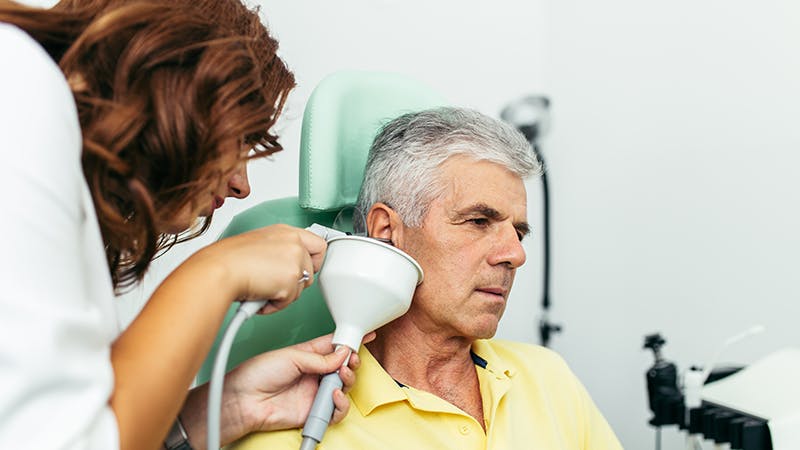 Physician examining a male patient's ear