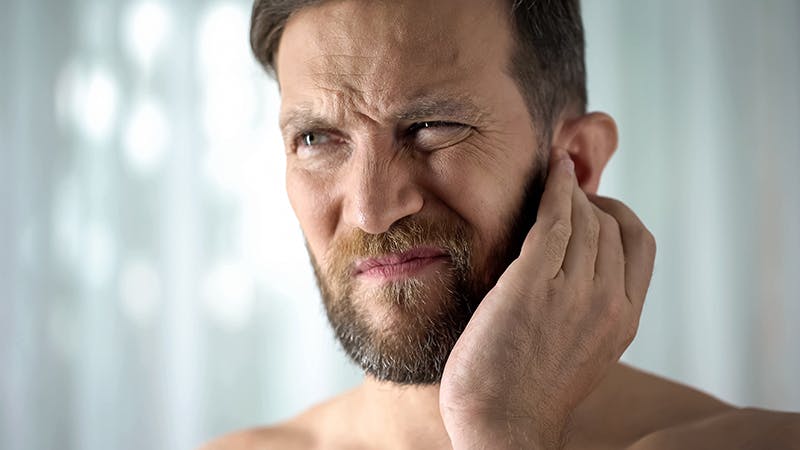 Man in pain holding his ear.
