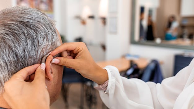 an image of a female doctor placing in a hearing aid