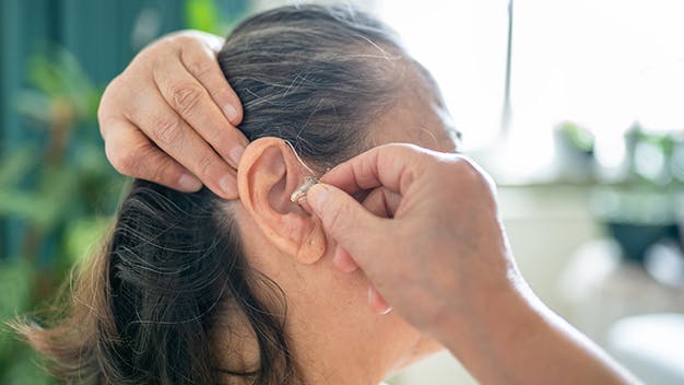 an image of a woman placing in a hearing aid