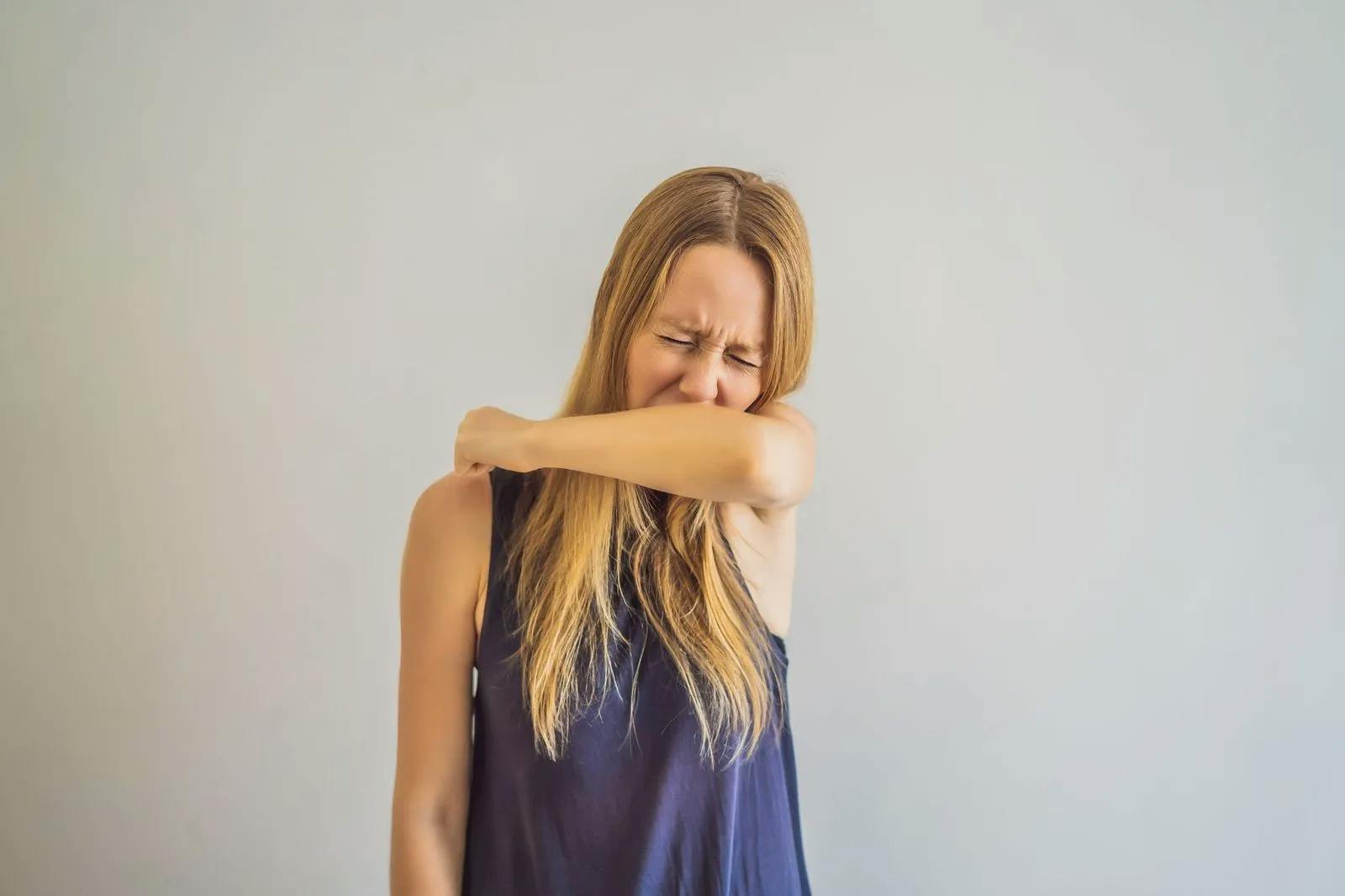 Woman sneezing into her elbow.