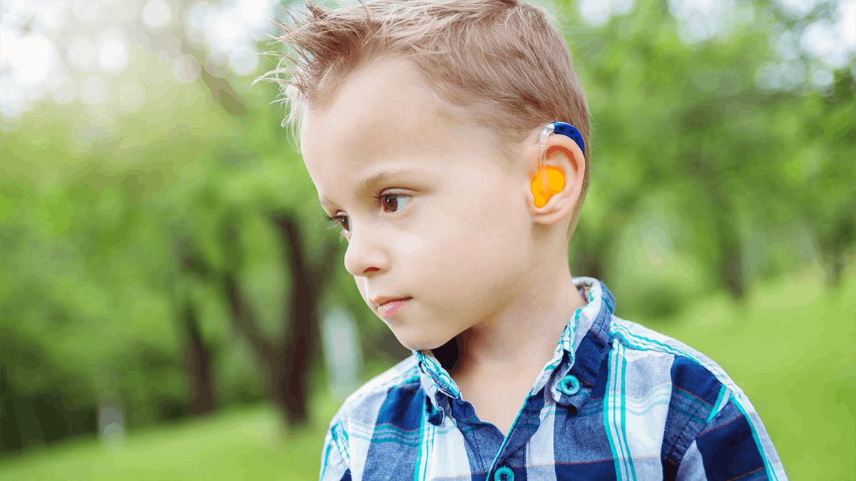 a young boy wearing a blue and yellow hearing aid