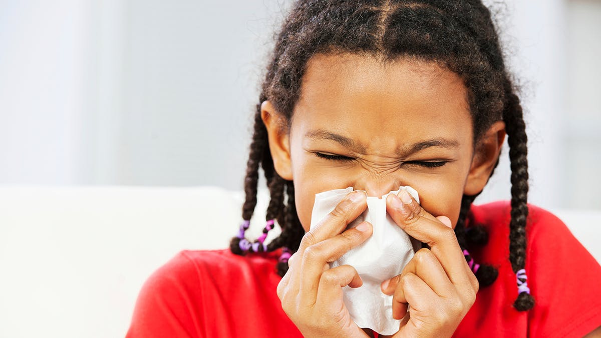 Child blowing their nose with tissue.