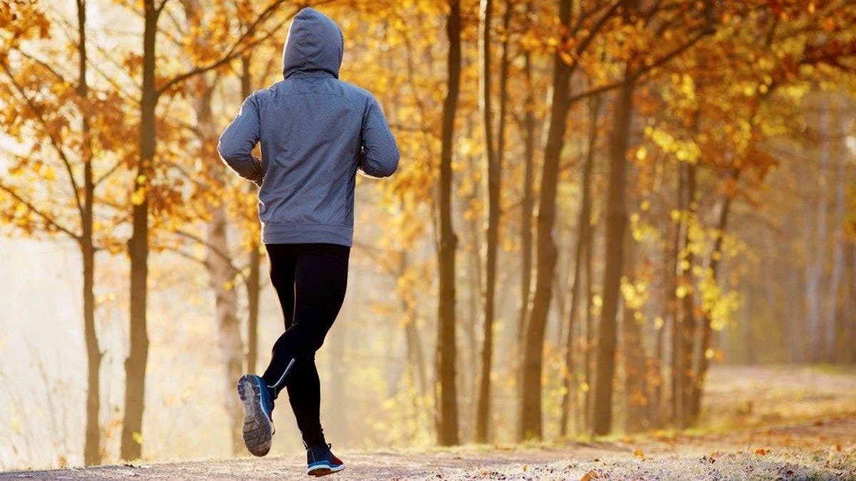 Person running on a path surrounded by trees.