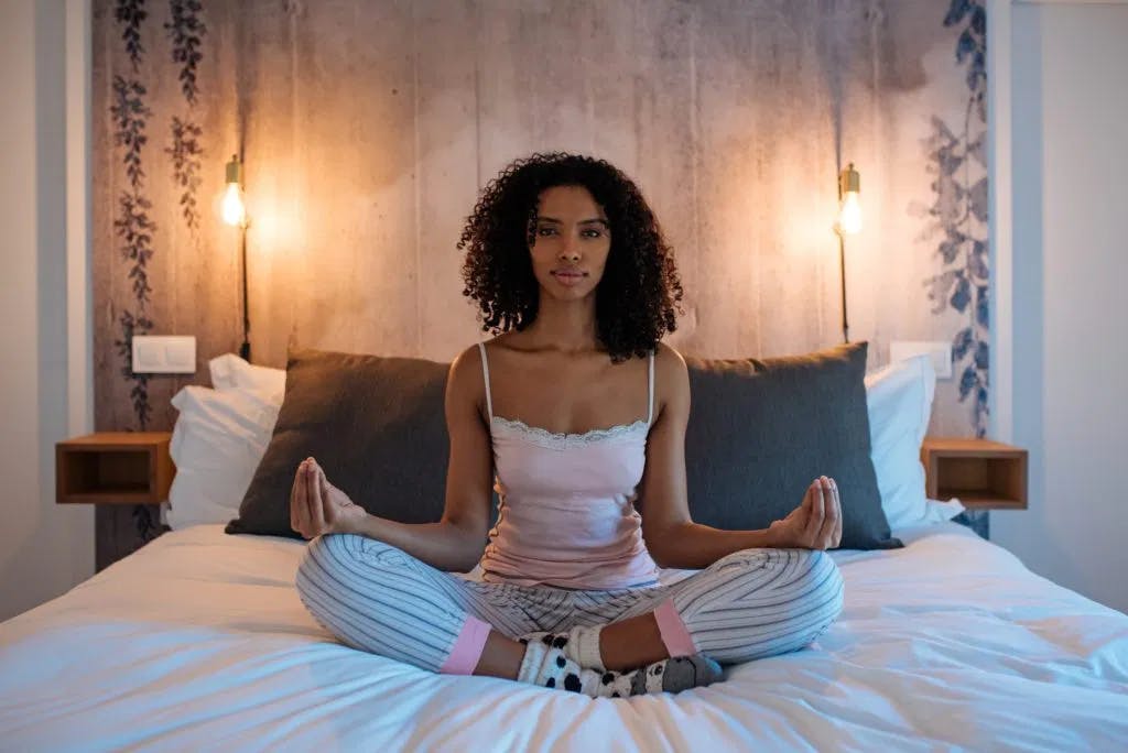 an image of a woman meditating in bed
