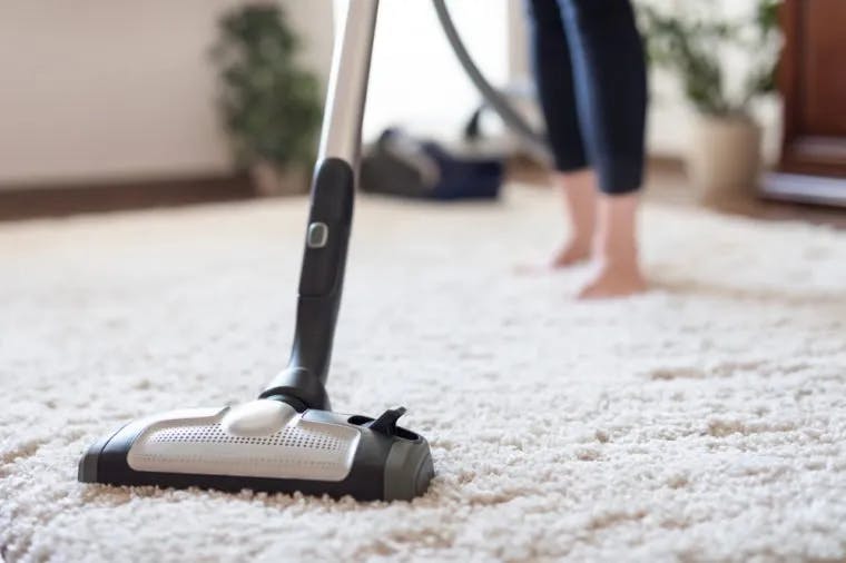 an close up of someone vaccuming their white rug