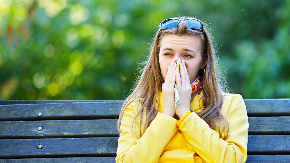 Younger woman in a yellow sweater, having allergy problems