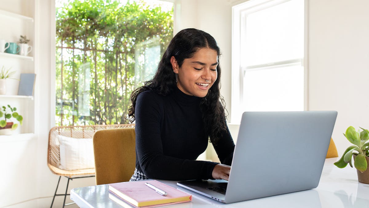 a woman at home working on her laptop in a black longsleeve turtle neck