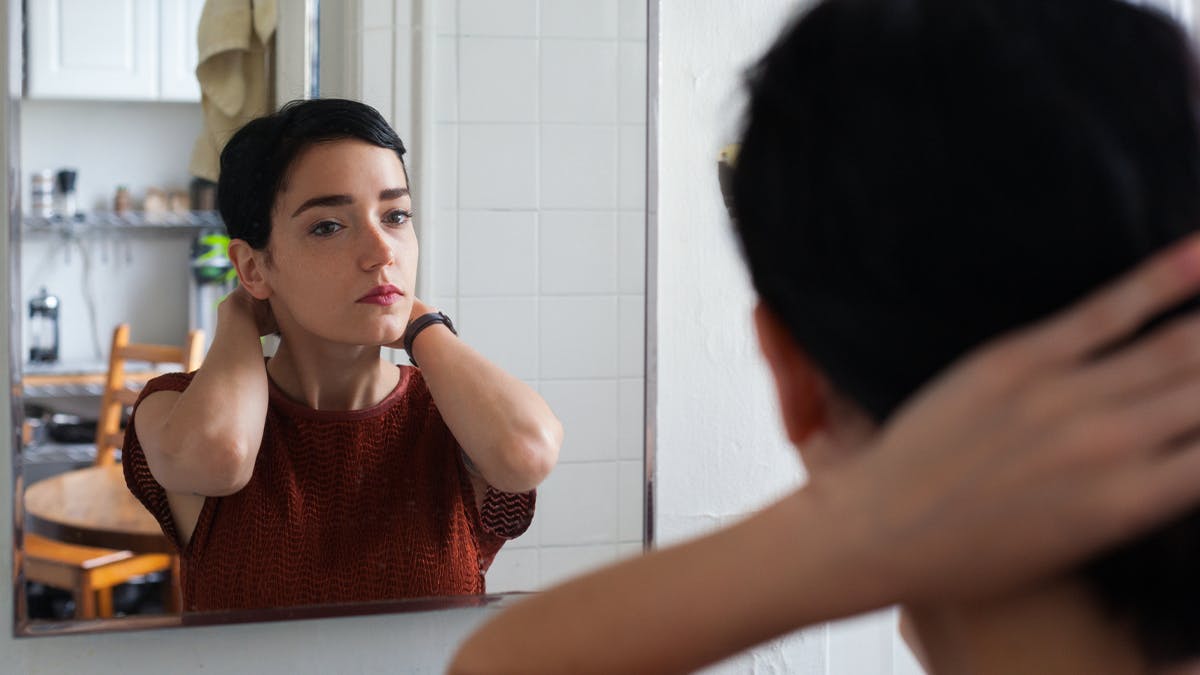 an image of a woman with short dark hair looking in the mirror