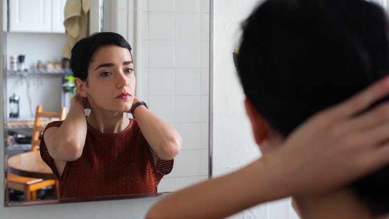 an image of a woman with short dark hair looking in the mirror