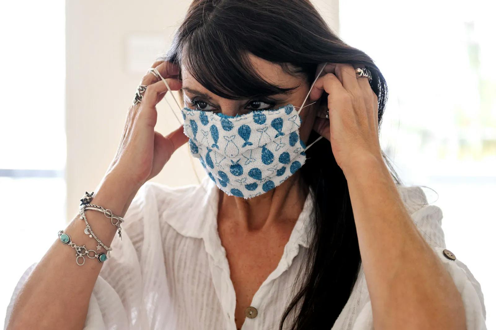 an image of a woman with dark hair putting on a mask