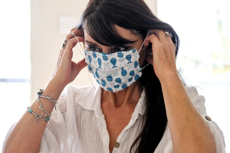 an image of a woman with dark hair putting on a mask