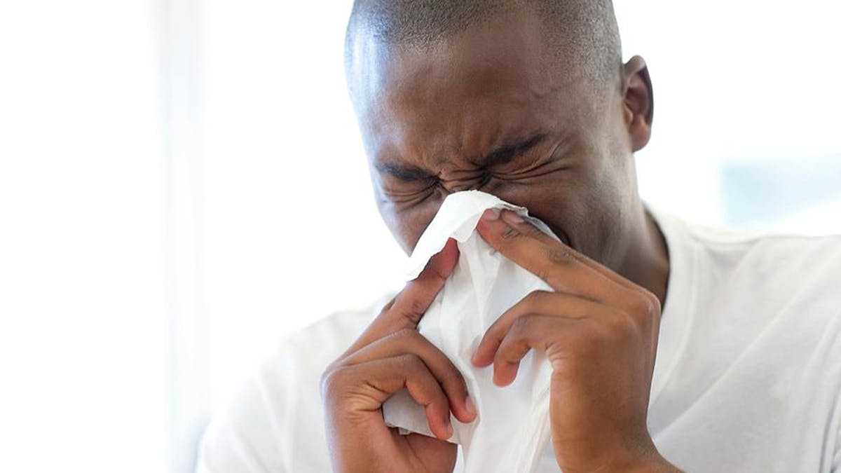 an image of a man blowing his nose into a tissue