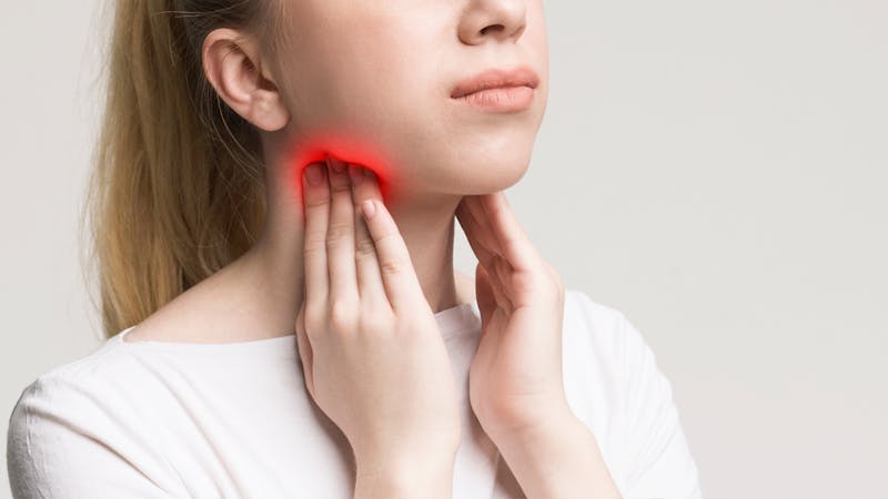 Woman holding pain spot near tonsils