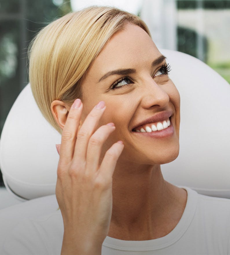 woman with blonde hair smiling in a white shirt