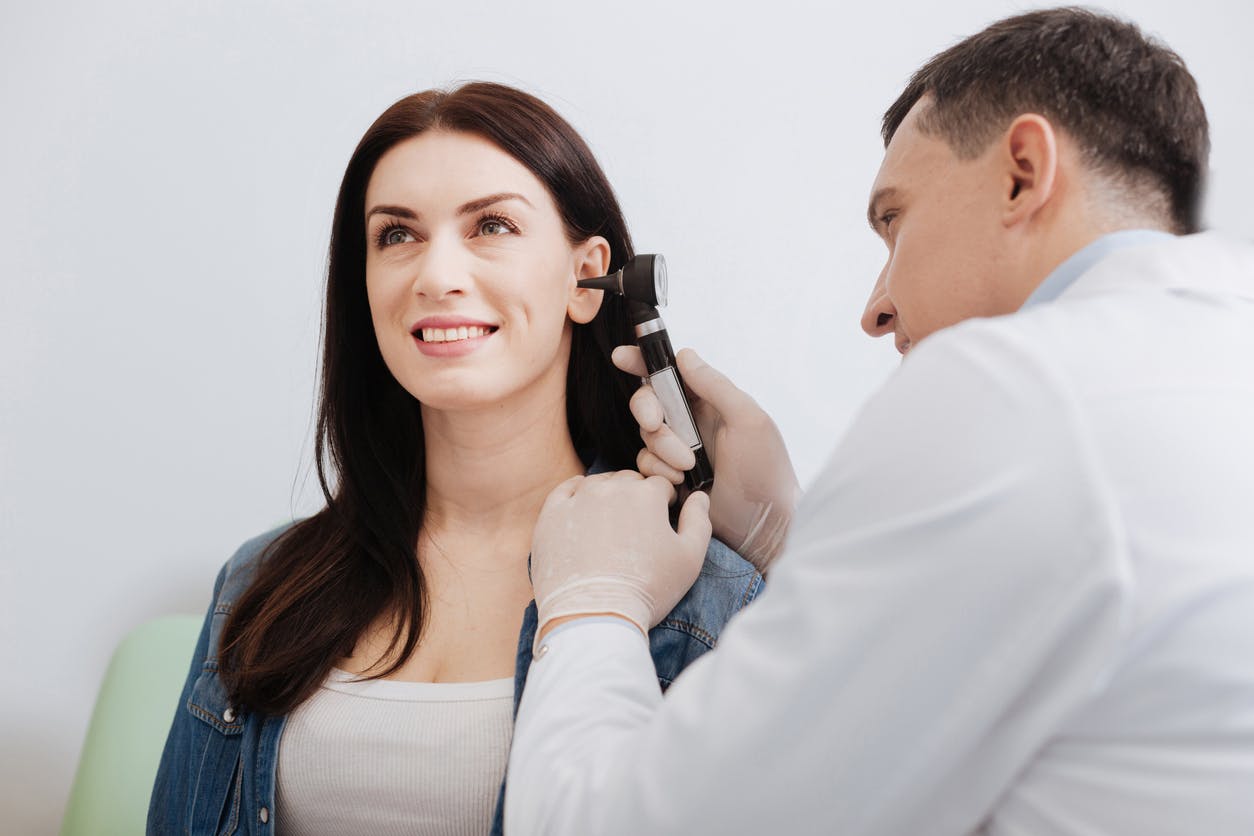 Woman getting her ear looked at by a doctor.