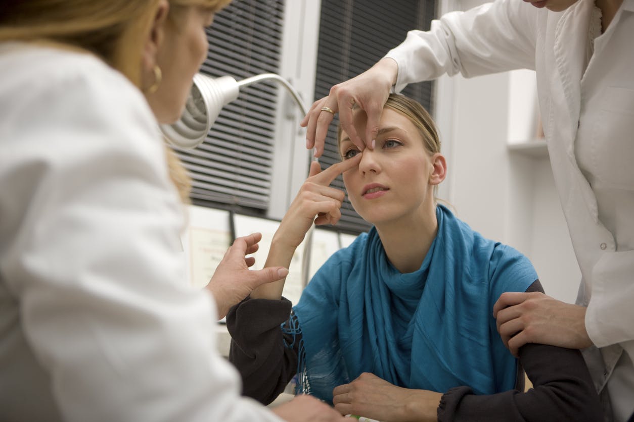 Two doctors examining a woman's nose