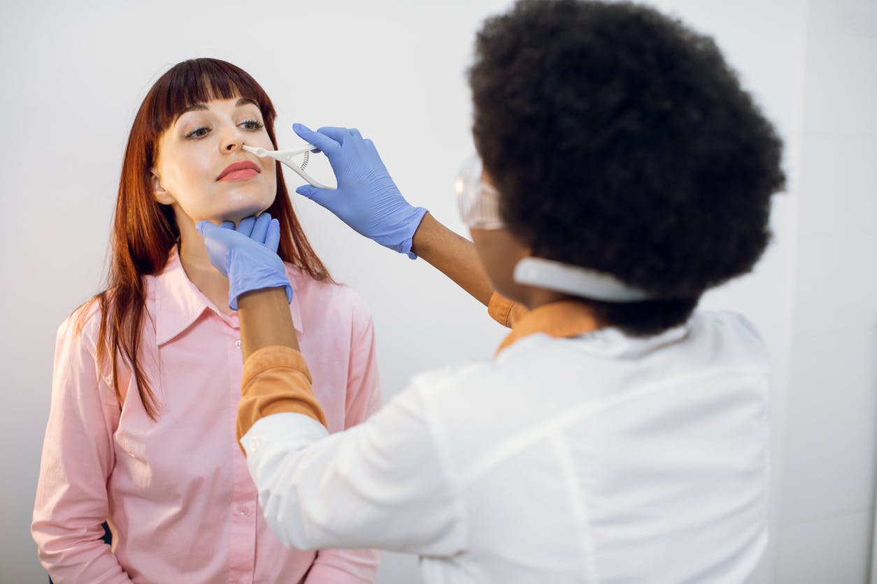 Physician examining a female patient's nose