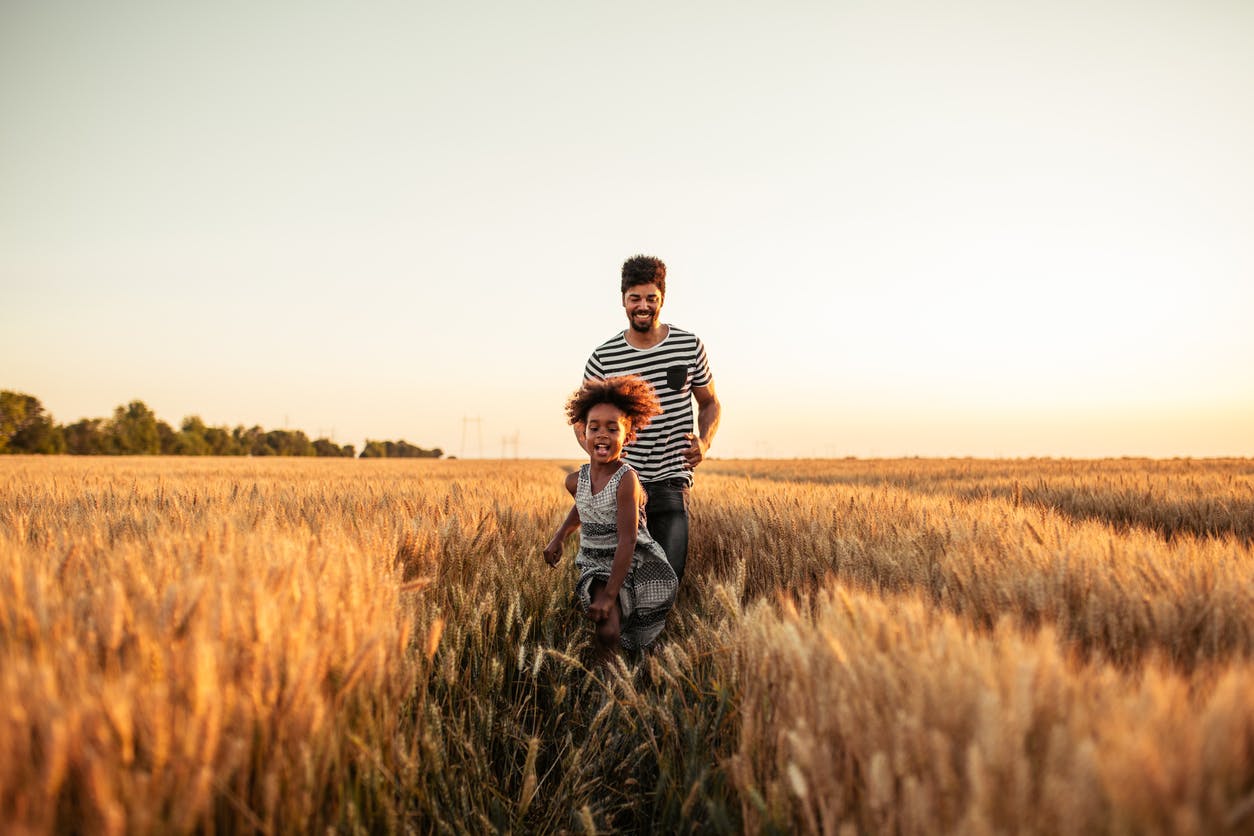 Man and daughter running through a field