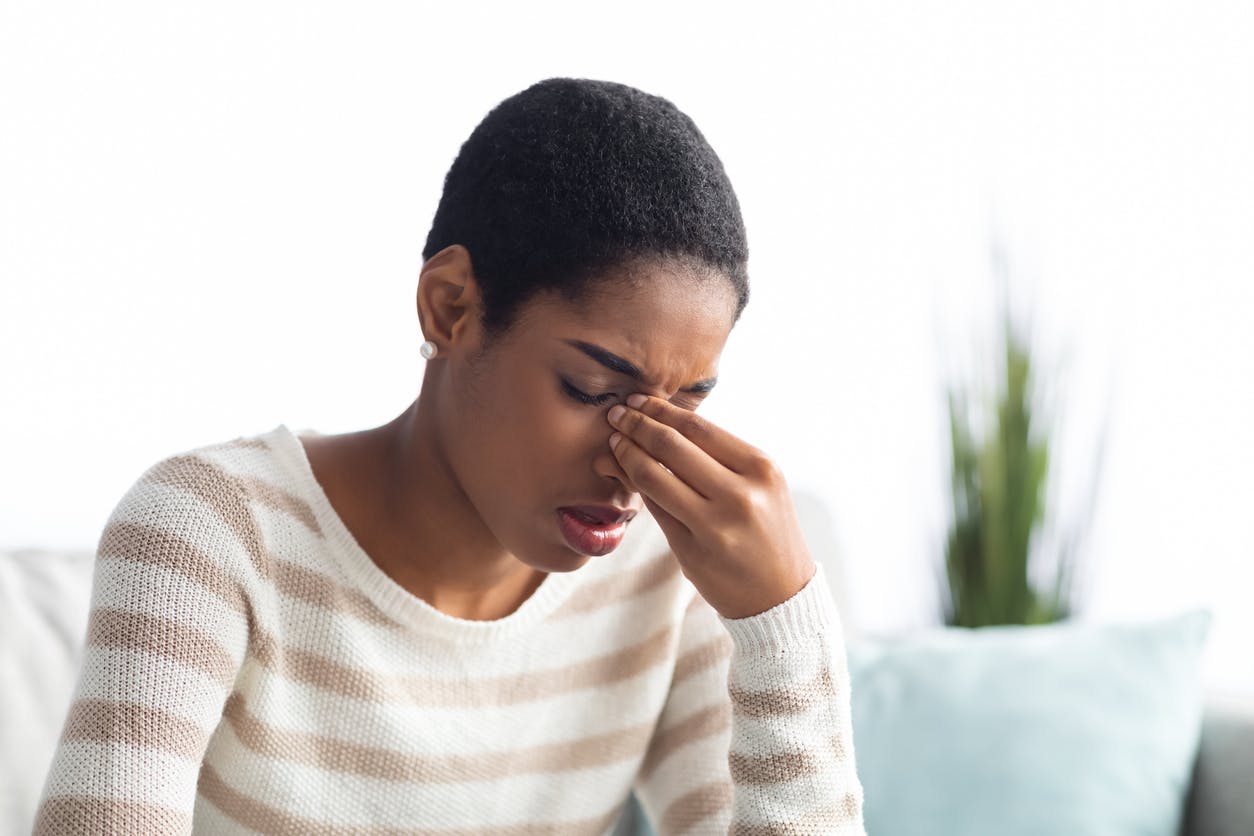 Woman grabbing her nose in discomfort/pain.