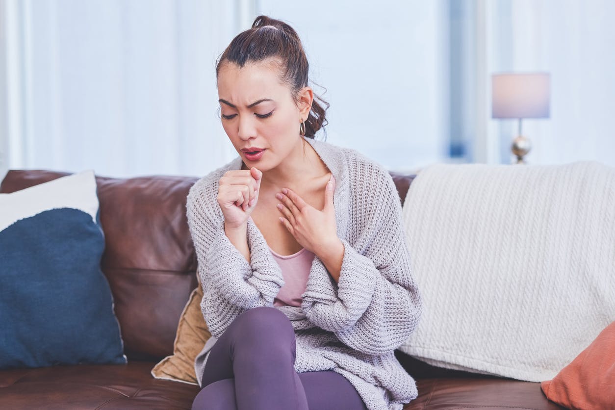 Woman coughing and holding her throat