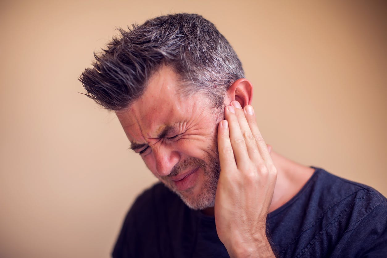 Man holding his left ear in pain